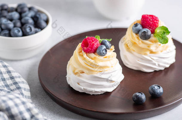 美味的<strong>巴</strong>甫洛娃蛋糕，奶油和新鲜的浆果放在木制盘子里。有选择的重点