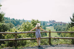 美丽的年轻女子看着风景如画的夏季乡村景观