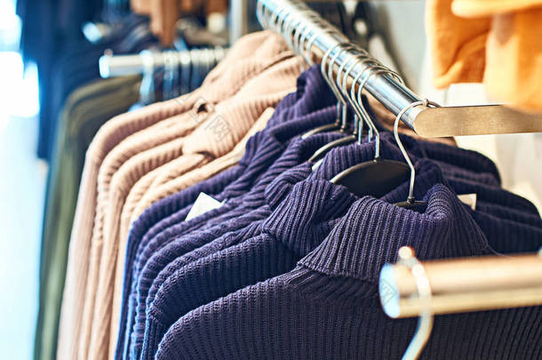 零售服装店的衣架上有不同颜色的女式套头毛衣.