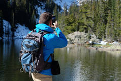 徒步旅行者与背包拍照与智能手机附近的熊湖秋季在洛基山国家公园。科罗拉多, 美国. 
