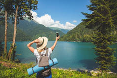 美丽的女孩旅行者使自拍在一个大的蓝色山湖在山的背景旅行概念夏天假期拷贝空间