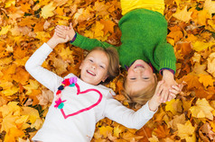 可爱小孩玩在秋天的公园里，躺在明亮的黄色和橙色树叶