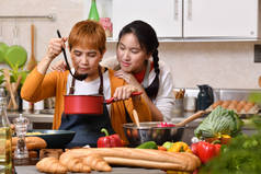 爱亚洲家庭的母亲和女儿在厨房做饭，一起做健康的食物，感觉很有趣