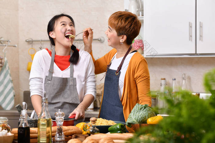 爱亚洲家庭的母亲和女儿在厨房做饭，一起做健康的食物，感觉很有趣