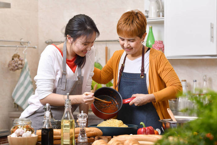 爱亚洲家庭的母亲和女儿在厨房做饭，一起做健康的食物，感觉很有趣