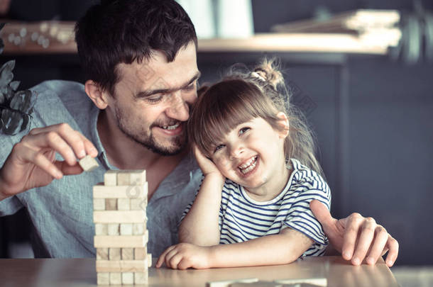 爸爸和他的女儿在餐桌上的咖啡馆玩耍, 父亲节和家庭价值观的概念