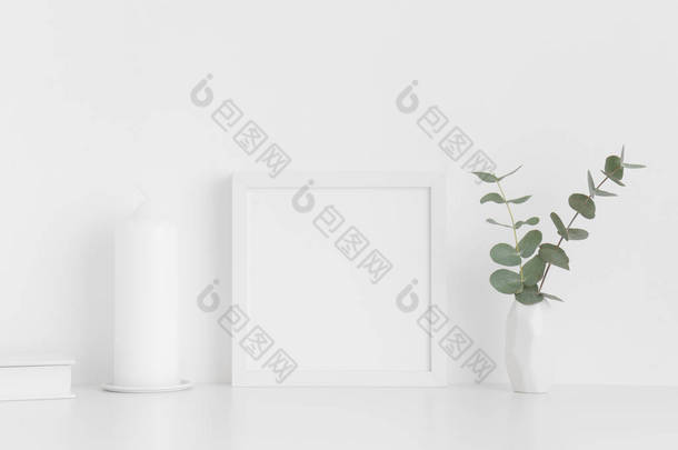 <strong>白色</strong>的<strong>正方形</strong>框架，<strong>白色</strong>桌子上的花瓶里装有工作空间配件和桉树.