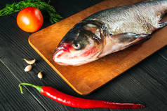 在烹调之前，将下丘脑或黑头鲤鱼放在带有蔬菜的切菜板上。在餐馆厨房里吃生鱼片.鱼类饮食理念