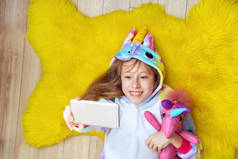穿着独角兽睡衣、头戴玩具的可爱女孩会自作主张，躺在地板上玩乐。顶部视图