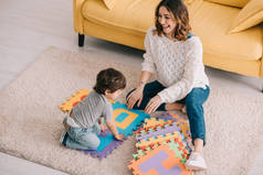母亲和儿子在地毯上玩字母拼图垫