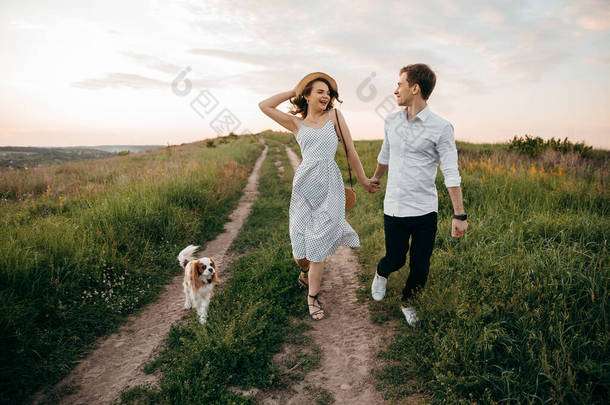 一对可爱的夫妇带着漂亮的狗在<strong>草地上奔跑</strong>