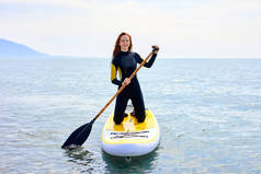 SUP站起来划桨板。在美丽平静的海面上航行的年轻女子