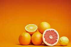 新鲜成熟的整体特写镜头视图和橙色背景上的柑橘切片水果