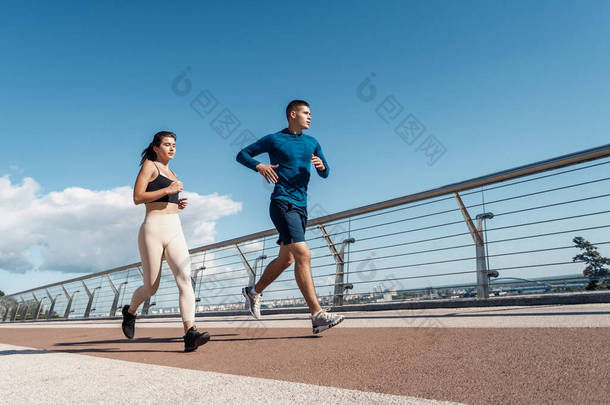 晨练的概念。男子和女子运动员在城市一起跑步，使户外运动训练的低视角视角