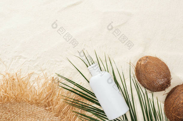 棕榈叶、椰子和防晒霜的顶视图化妆水带草帽的沙上