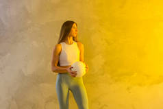 排球比赛女子持球和踢球在黄色混凝土墙的背景.运动员在家里做运动锻炼.体育和娱乐概念