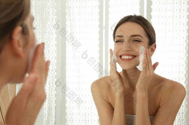 在浴室靠近镜子的地方用洁面泡沫擦拭自己的脸