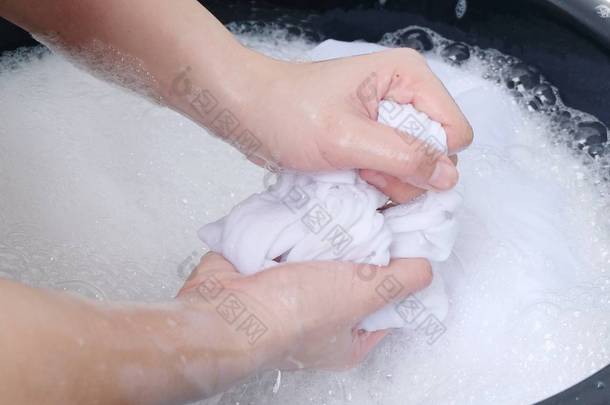 <strong>一个</strong>女人在肥皂水中用手洗衣服, 在白色的背景上被隔离