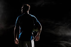 足球运动员的剪影与球在黑色与烟雾  