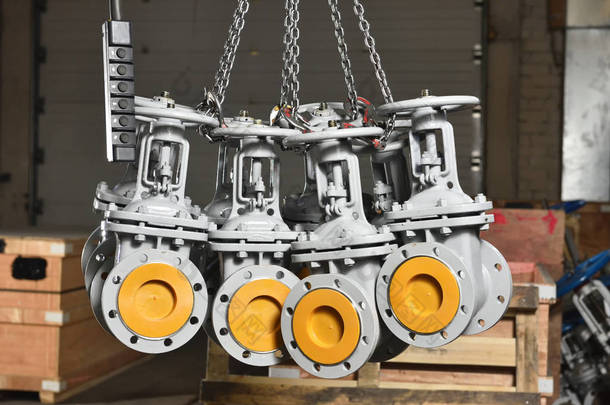 新的灰色机械式阀门悬挂在工业电梯的链条上. 水阀或气阀悬挂在工厂的链条中.