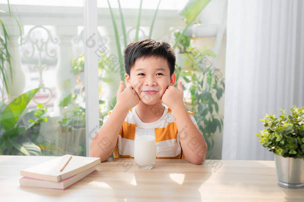可爱的年轻的亚洲男孩，早上在家里吃早餐和喝牛奶；看着<strong>相机</strong>