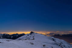 都灵城的灯火, 夜观从白雪覆盖的阿尔卑斯月光下。月亮和猎户星座, 晴朗的天空。意大利.