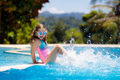 孩子们在游泳池里玩耍。和孩子们一起过暑假在热带岛屿度假胜地的异国情调假日，小女孩跳入水中。孩子们游泳。幼儿积极参加户外运动.