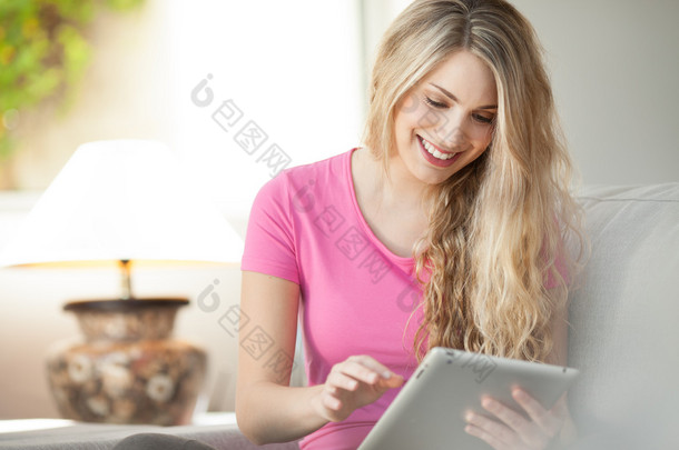 年轻漂亮的女人在家里使用平板电脑