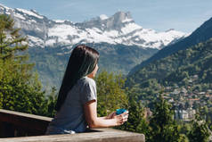 女孩拿着杯子, 而站在阳台上, 看风景秀丽的山, 勃朗峰, 阿尔卑斯
