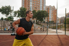 篮球运动员准备在室外场地上投篮. 身穿运动服的男子运动员在街头篮球训练中持球