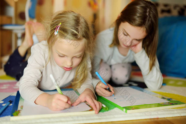 两个可爱的小妹妹在家里一起写信。姐姐帮助年轻人做作业.