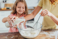 与女儿一起把牛奶倒入玻璃碗时，妇女揉面的剪影