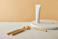 大理石圆板与牙膏在管和竹子牙刷在白色桌子和米色背景