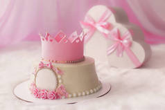 粉红色蛋糕与皇冠和礼物在心脏盒为漂亮的女孩生日聚会