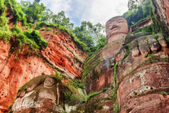 乐山大佛的底视图。背景是绿树和蓝天。在中国峨眉山风景区, 世界上最大、最高的石佛雕像是由红色悬崖雕刻而成的.