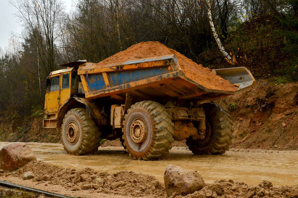 在采石场工作的黄色大柴油卡车。运送砂土的重型矿用卡车。Belaz案.