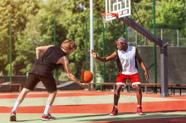 非洲裔美国人和白人篮球运动员在室外赛场上玩游戏
