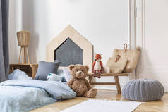 时尚的儿童卧室在公寓的房子。镶木地板上的灰色布夫，带包和玩具的木桌，带蓝色床上用品的床.