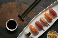 握寿司套装、筷子、酱油在深色表面白盘子上的全景