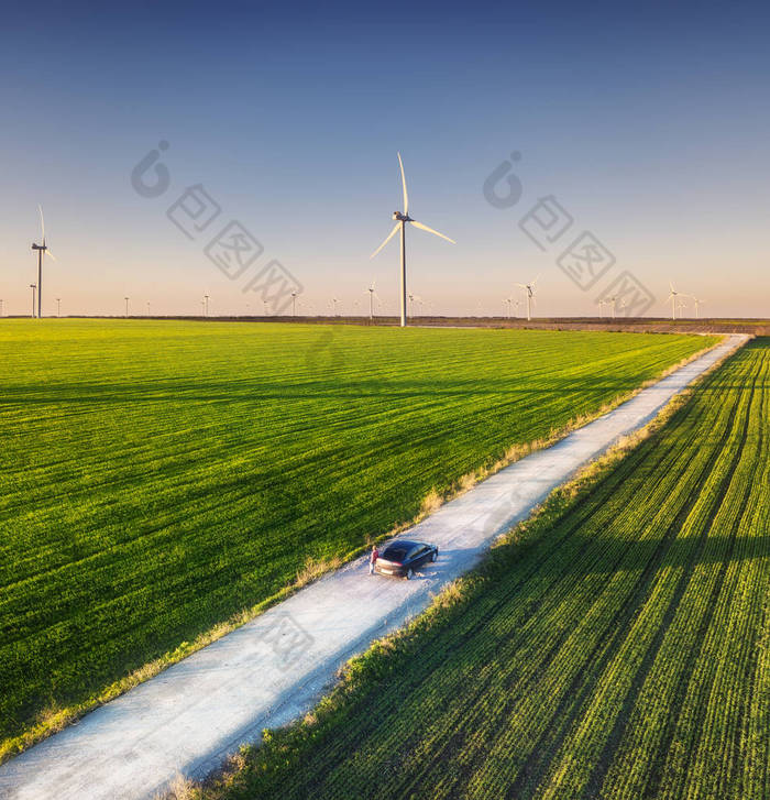 日落时在美丽的夏场上的道路鸟图。景观与农村公路、风力涡轮机。穿过田野的路。从飞行无人机的顶部视图。旅游形象