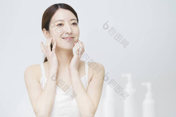 一个白色的瓶子，有一个女人摸着她的脸进行皮肤护理