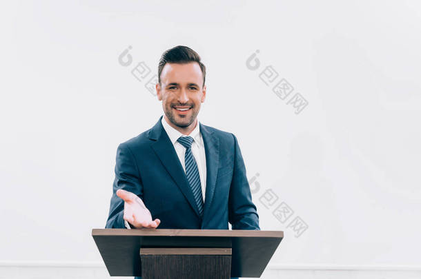 在会议厅的研讨会上, 微笑讲师站立和手势在讲台论坛