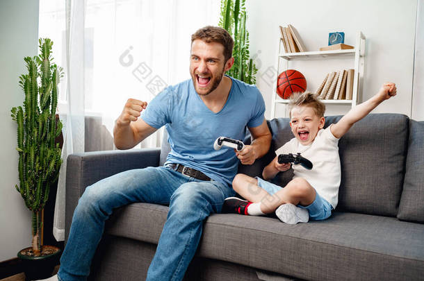 爸爸和他的小儿子<strong>在家</strong>里一起玩电子游戏
