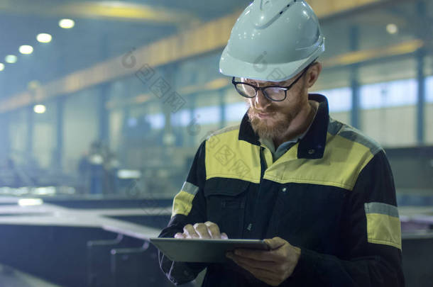 工程师在安全帽在重型工业中使用一台平板电脑