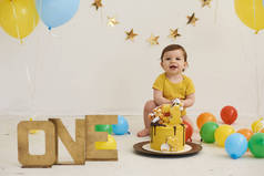 可爱可爱可爱的白人男孩用蛋糕和气球庆祝他的第一个生日的画像