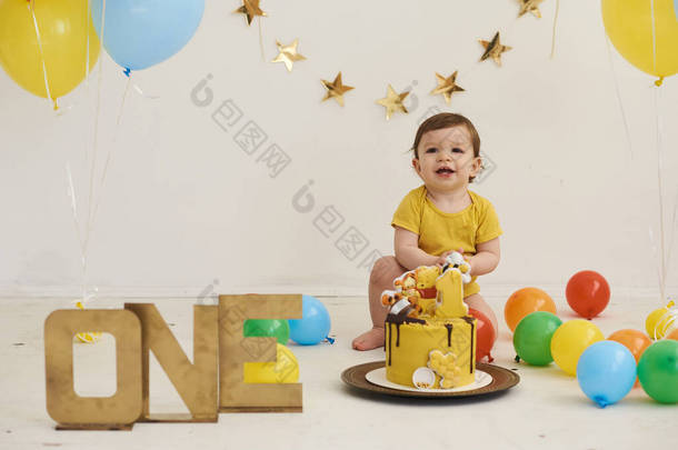 可爱可爱可爱的白人男孩用蛋糕和气球庆祝他的第一个生日的画像