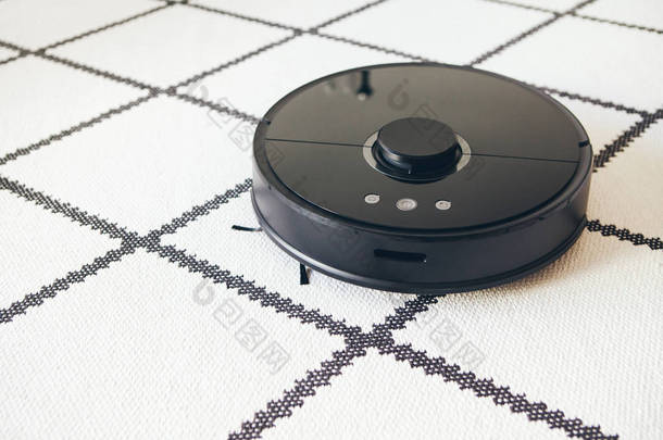 具有智能导航功能的真空机器人清洁剂正在做家务--清洗白色地毯。远程和电话控制。扫地功能