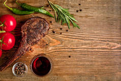 烧烤干岁的肋的牛肉、 蔬菜以及玻璃的木底白字红葡萄酒特写