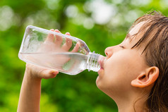 女孩从透明的塑料瓶饮用清洁的自来水