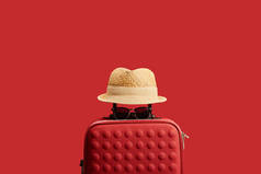 红色旅行袋与草帽和太阳镜隔离在红色 